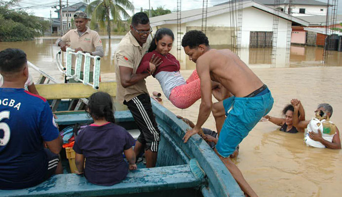 Ravi Kalpoo, centre, of Klapoo Tours is assisted by a villager during efforts to help marooned flood victims in central Trinidad.  -Photo: Courtesy Kalpoo Tours Ravi Kalpoo, centre, of Klapoo Tours is assisted by a villager during efforts to help marooned flood victims in central Trinidad.  -Photo: Courtesy Kalpoo Tours