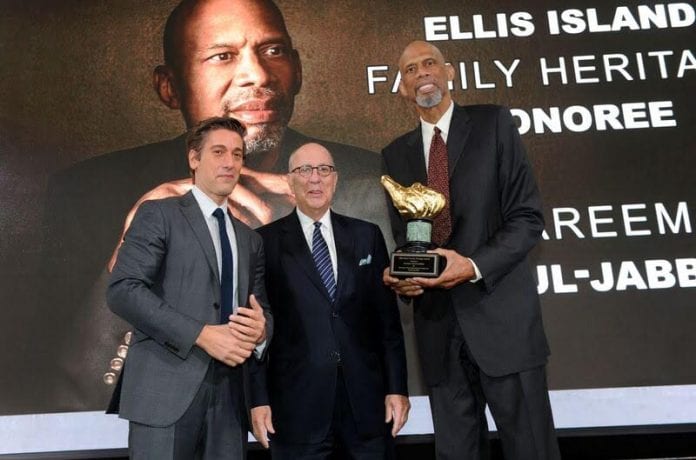 Basketball legend Kareem Abdul-Jabbar (right) receives the 2017 Ellis Island Family Heritage Award from host David Muir ( left), anchor and managing editor of ABC World News Tonight, and Stephen Briganti, president and CEO, Statue of Liberty-Ellis Island Foundation. The occasion took place October 24, 2017 at Ellis Island in New York. Photo credit: Diane Bondareff/Invision for Statue of Liberty-Ellis Island. Basketball legend Kareem Abdul-Jabbar (right) receives the 2017 Ellis Island Family Heritage Award from host David Muir ( left), anchor and managing editor of ABC World News Tonight, and Stephen Briganti, president and CEO, Statue of Liberty-Ellis Island Foundation. The occasion took place October 24, 2017 at Ellis Island in New York. Photo credit: Diane Bondareff/Invision for Statue of Liberty-Ellis Island.